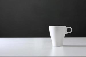 White cup on gray background. Blank ceramic cup photo