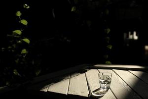 a glass of water on a white table with rays of the sun with nature background photo