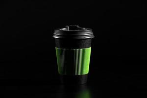 a glass of hot tea or coffee. Black paper glass with a lid on a black background. side view photo