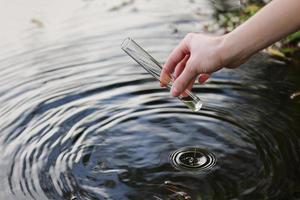 muestra de agua. mano recoge agua para explorar. concepto: análisis de la pureza del agua, medio ambiente, ecología. pruebas de agua para detectar infecciones, permiso para nadar. enfoque selectivo, lugar para el texto. foto