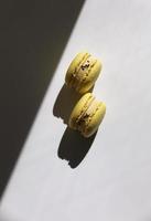patrón abstracto con macarons amarillos o macarons sobre fondo blanco con sombras. patrón sin costuras delicioso postre francés saludable. concepto moderno mínimo creativo. foto