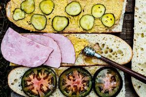 ham sandwich preparation with mustard and pickles photo