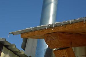 Icicles of ice hang on the structure of the roof of the house photo