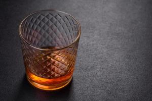 A glass of whiskey or cognac on a black concrete table. Relaxation time photo