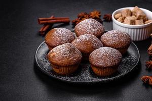 Beautiful delicious cupcakes with cocoa and raisins on a black concrete background photo