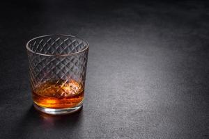 A glass of whiskey or cognac on a black concrete table. Relaxation time photo