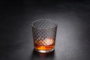 A glass of whiskey or cognac on a black concrete table. Relaxation time photo