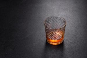 A glass of whiskey or cognac on a black concrete table. Relaxation time