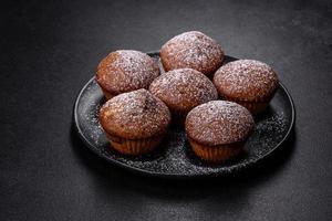 Beautiful delicious cupcakes with cocoa and raisins on a black concrete background photo