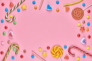 Sweet candy copy space frame with lollipops on pink background photo