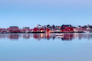 almacén de pesca rojo con reflejo de barco de pesca en la costa foto