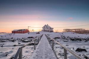 White house with wooden bridge and frozen coastline photo