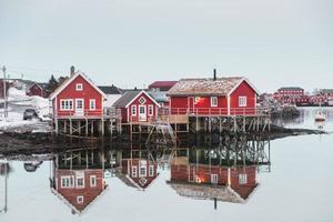 pueblo escandinavo con reflejo de la casa roja en el océano ártico foto