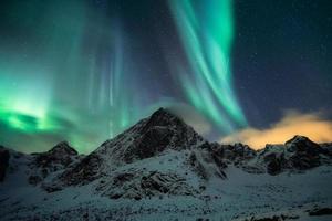 aurora boreal, aurora boreal con estrella sobre el pico de la montaña nevada en invierno foto