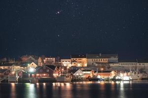 Norwegian village illumination with fishing boat on coastline with stars in the night sky