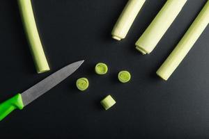 Minimal flat lay looking leeks view during slice progress over black, indludes copy space. photo