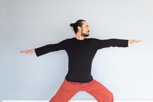 Young Caucasian long haired white man is performing yoga in a studio or house. photo