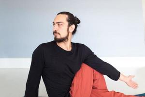 Young Caucasian long haired white man is performing yoga in a studio or house. photo