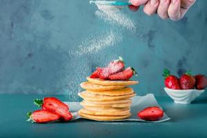 Anonymous hand is serving powder sugar to pancake stacks. Includes copy space. photo