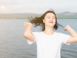 Asian girl in white shirt smiling Hands flick the hair so that it doesn't become tangled. blown by the wind Challenge the wind at the sea and the sun On the day when she came out on vacation photo