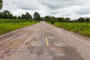 Damaged asphalt pavement road with potholes photo