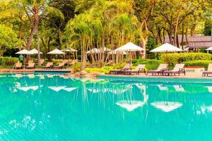 Umbrella and chair around swimming pool in resort hotel for leisure travel and vacation neary sea ocean beach photo