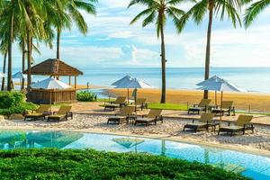 Beautiful luxury umbrella and chair around outdoor swimming pool in hotel and resort with coconut palm tree on sunset  or sunrise sky photo
