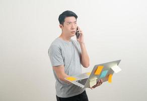 Asian man talking smartphone or mobile phone and hand holding laptop photo