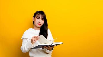 A young woman reads a book and is thinking like a movie. on a yellow background photo