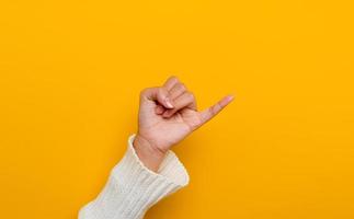 The promise of a white Asian woman's hand little finger split on yellow background gestures of commitment and reconciliation photo
