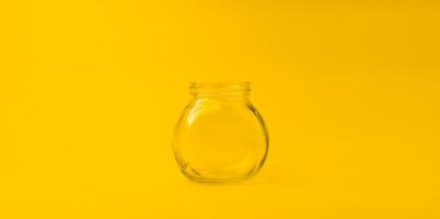 empty glass jar on a yellow background with free space photo