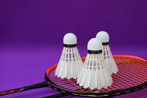 White cream badminton shuttlecock  in front of badminton rackets on purple floor of indoor badminton court, soft and selective focus on shuttlecock, concept for badminton sport lovers around the world photo