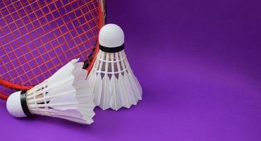 volante de bádminton de crema blanca frente a raquetas de bádminton en el suelo morado de la cancha de bádminton interior, enfoque suave y selectivo en el volante, concepto para los amantes del deporte de bádminton en todo el mundo foto