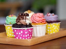 Colorful of homemade cupcake in wooden Tray on wooden table. photo