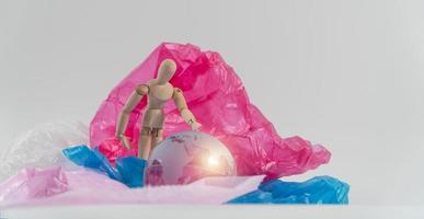 la marioneta de madera toca el globo de cristal en la bolsa de plástico y se preocupa y tiene que proteger la tierra. Los desechos plásticos inundan el mundo. concepto de calentamiento global y cambio climático.