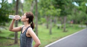 young asian woman runner doing drinking water photo