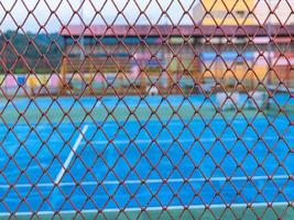 Steel panels form a fence around the tennis court to prevent tennis balls from injuring passersby and make it easier to pick up tennis balls. photo