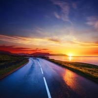 carretera asfaltada a lo largo del mar al atardecer islandia foto