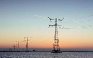 Electric poles in the water at sunset photo