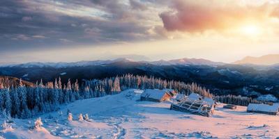 Fantastic sunset over snow-capped mountains and wooden chalets. photo