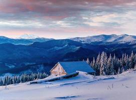 Fantastic sunset over snow-capped mountains and wooden chalets photo