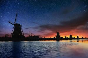 Starry sky over Dutch windmills from the canal in Rotterdam photo