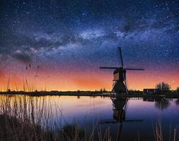 Starry sky over Dutch windmills from the canal in Rotterdam photo