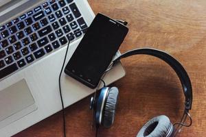 portátil y teléfono con auriculares sobre la mesa. foto