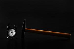 wake up with a hammer on a black background. Black old style alarm clock isolated photo