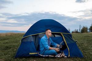 male freelancer is working on a laptop outdoors in mountains. Freelance concept. photo