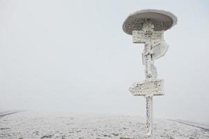 Frozen pointer with directional arrows at mountains photo