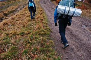 Rear view of two tourists with travel backpacks going up on mountain photo