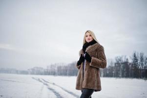 retrato de joven elegancia chica rubia en un abrigo de pieles río niebla de fondo en el hielo de invierno. foto