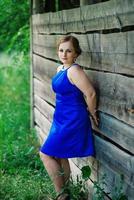 joven con sobrepeso en vestido azul posó jardín de primavera de fondo.